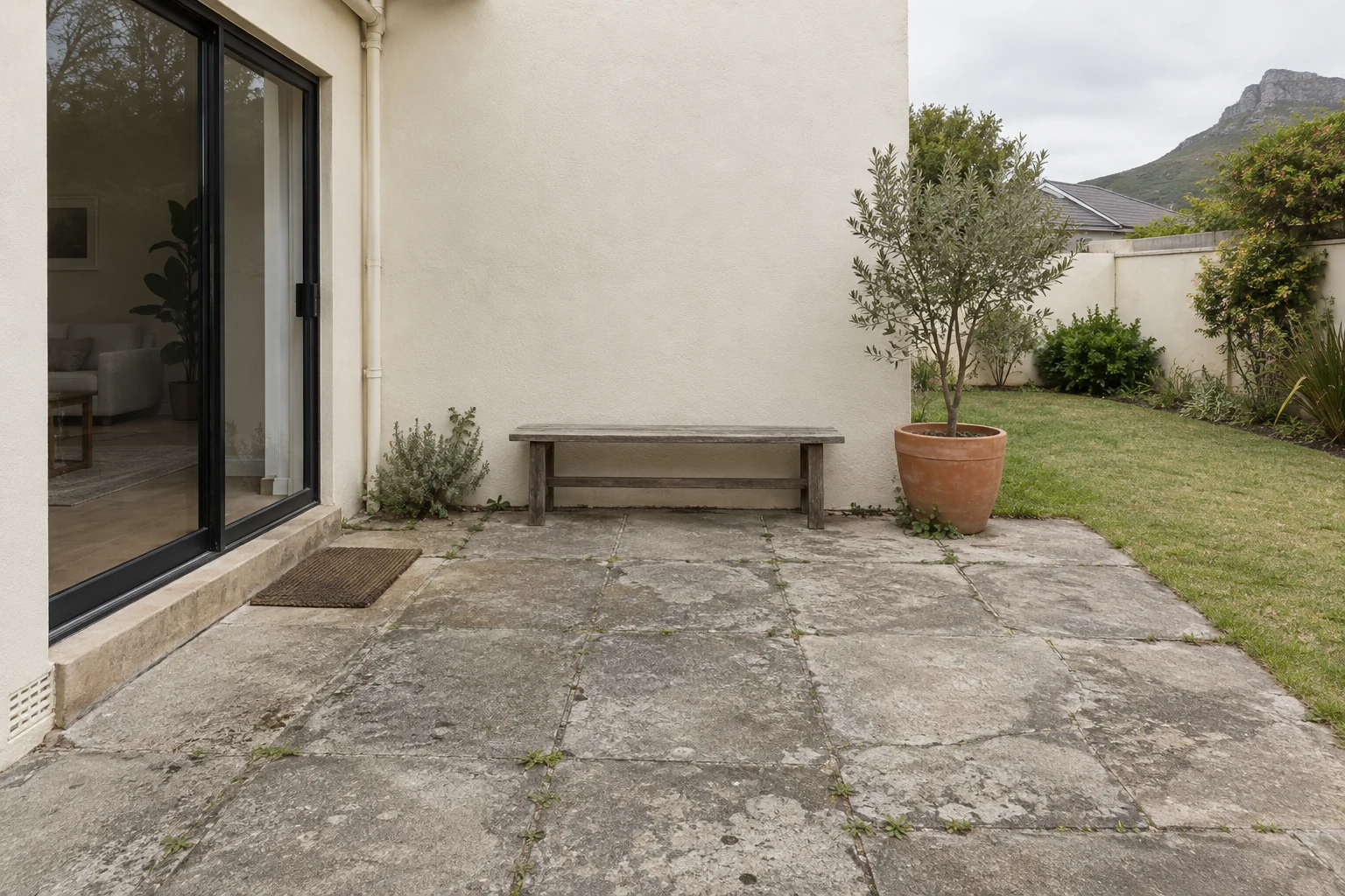 Generated view of a worn concrete patio beside a fictional Cape Town home