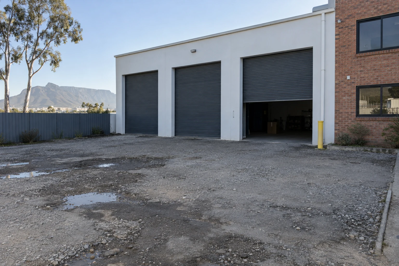 Generated before view of a gravel and asphalt apron outside a fictional Cape Town warehouse